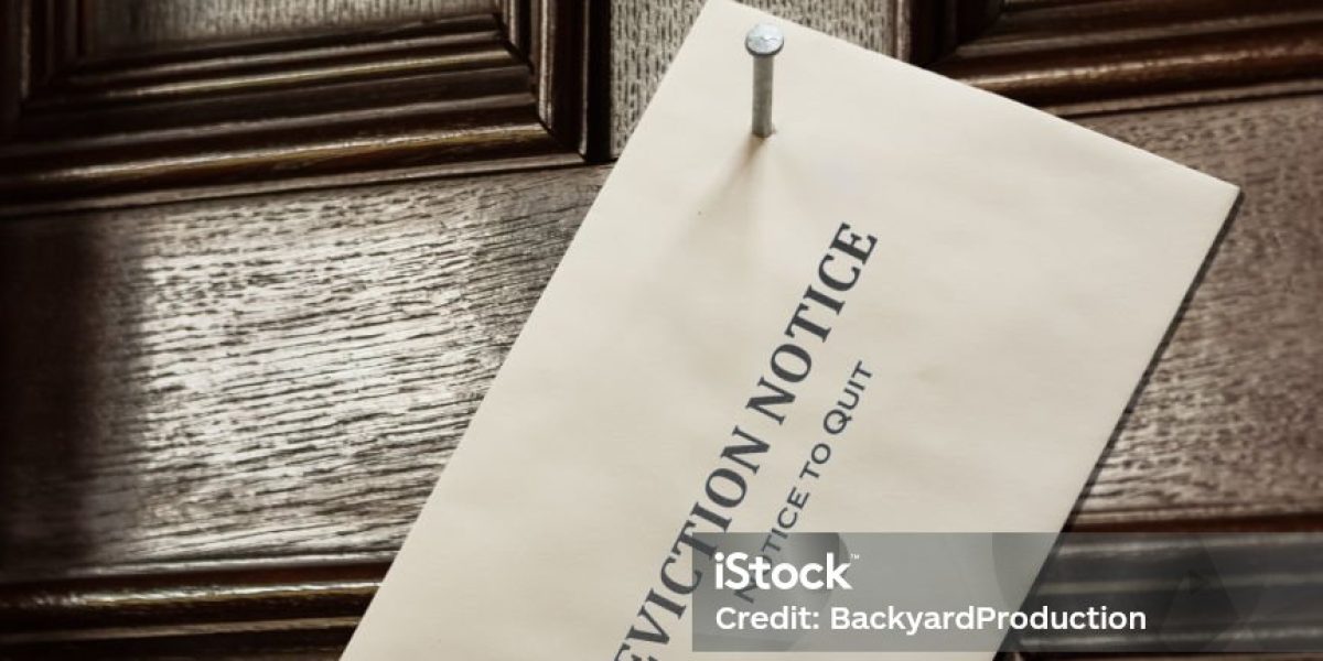 Envelope nailed to an old wooden door with a large nail in containing an eviction notice due to failure to pay rent